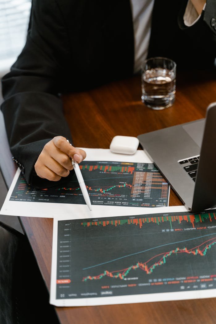 hero-img-01 Close-up of a business analyst reviewing printed financial graphs and charts at an office desk.